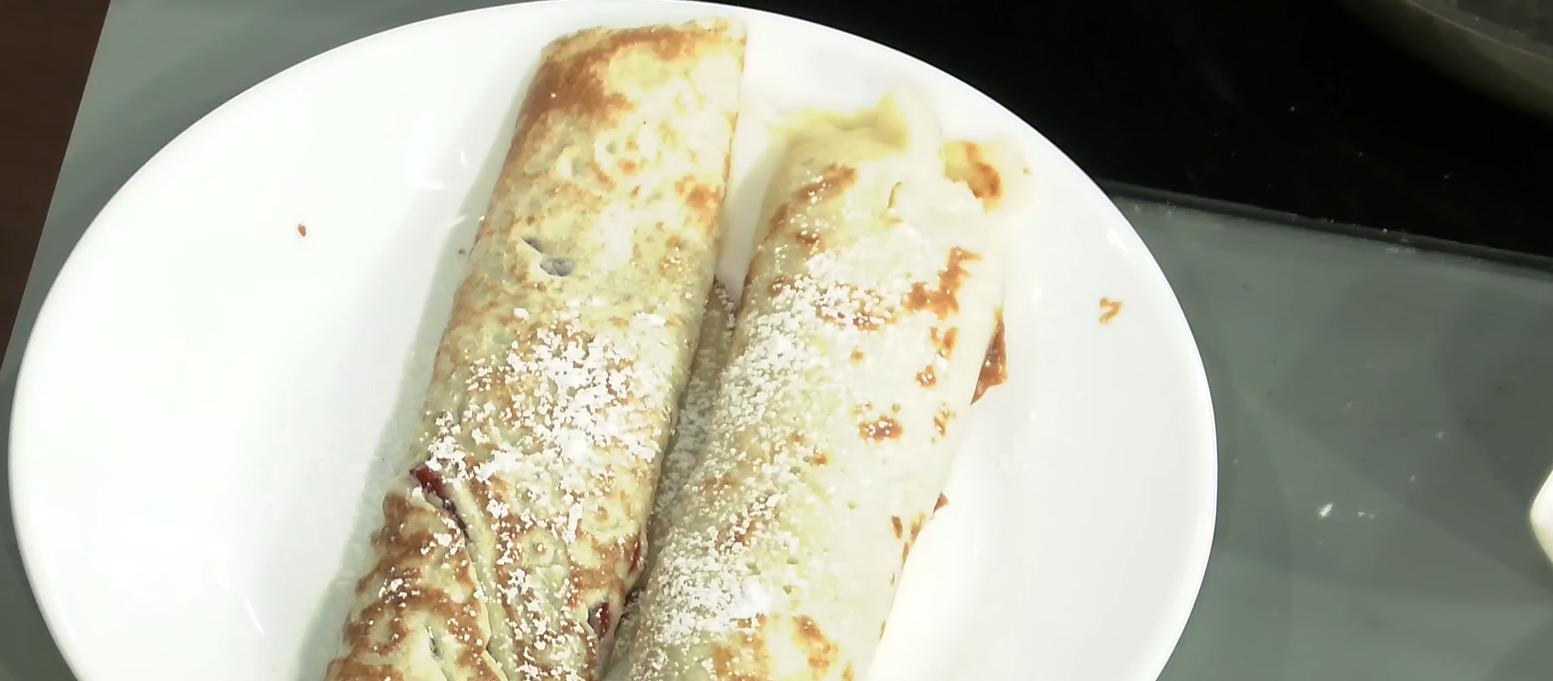 Dos panqueques con azúcar flor puestos encima de un plato blanco